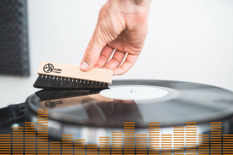 A person cleans a LP with a brush